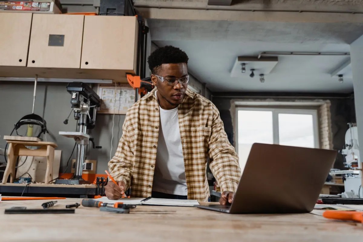 A craftsperson planning a project at a woodworking bench